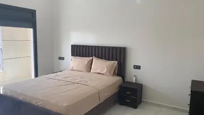 a bed with two pillows and a night stand in a bedroom at Near University Balcony in Fès