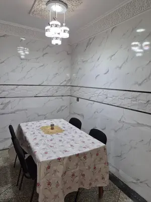 a dining room with a table and chairs and white marble walls at Villa avec piscine-Meknès in Oulad Akkou
