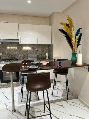 a kitchen with a table and two stools at cosy studio au coeur de casablanca in Oulad Akkou