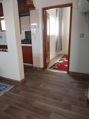 a room with a kitchen with wooden floors and an open door at Appartement massira in Beni Mellal