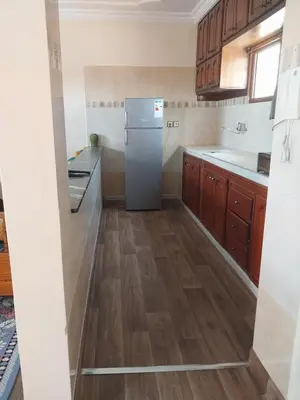 a kitchen with a refrigerator and wooden floors at Appartement massira in Beni Mellal