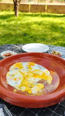 a red plate of food on a table at La ferme d'hôtes des lacs in Sefrou