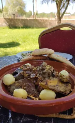 a bowl of meat and potatoes on a table at La ferme d'hôtes des lacs in Sefrou