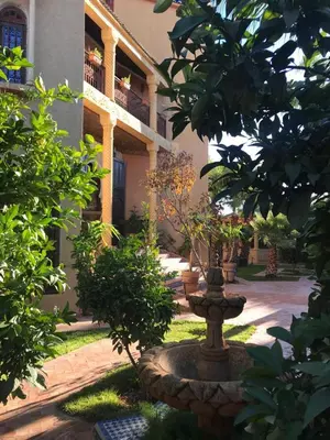 a courtyard with a fountain in front of a building at Les Jardins de Ryad Bahia in Meknès