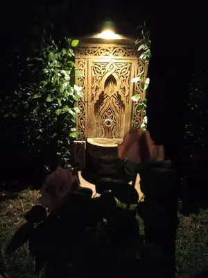 a door with a carving on it in a garden at night at Les Jardins de Ryad Bahia in Meknès