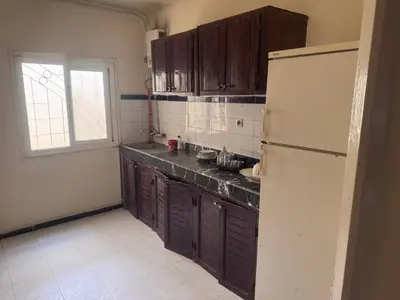 a kitchen with wooden cabinets and a white refrigerator at الامان والهدوء in Khemisset