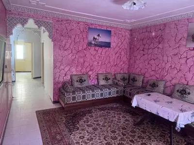 a living room with a couch and a pink wall at الامان والهدوء in Khemisset