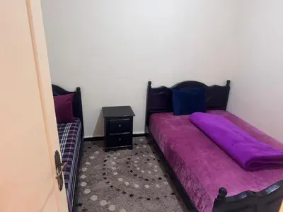 a bedroom with two beds with purple sheets at الامان والهدوء in Khemisset