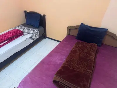 a small bedroom with a bed with purple sheets and blue pillows at الامان والهدوء in Khemisset