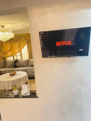 a television on a wall in a room with a table at Appartement de Luxe Fes Centre Ville in Fès