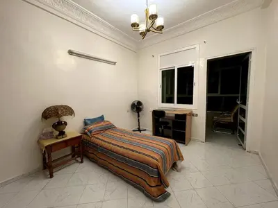 a bedroom with a bed and a table and a window at Spacious 140m Family Flat with air conditioner in Fès