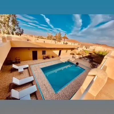 a house with a swimming pool in the desert at Hotel Dar Sahara in Merzouga