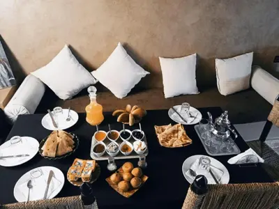 a table with food on it with a couch at Hotel Dar Sahara in Merzouga