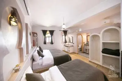 a hotel room with two beds and a bathroom at Hotel Dar Sahara in Merzouga