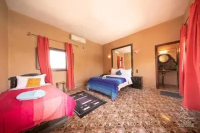 a bedroom with two beds and a mirror at Hotel Dar Sahara in Merzouga
