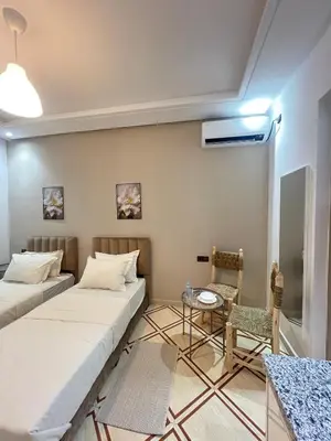 a room with two beds and a table and a chair at Charment studio avec terrasse in Er Rachidia