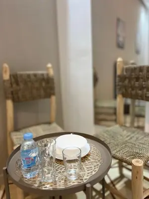 a table with a plate and glasses and a bottle of water at Charment studio avec terrasse in Er Rachidia