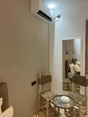 a room with a table and chairs and a mirror at Charment studio avec terrasse in Er Rachidia