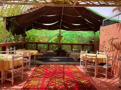 a patio with tables and chairs and a tent at Ecogite La Tourterelle - Guesthouse in Kalaat MGouna