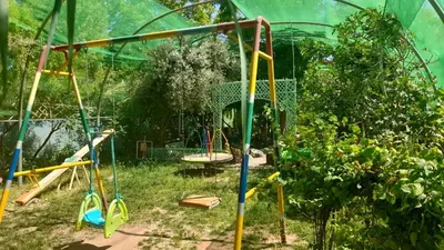 a playground in a garden with a swing at Ecogite La Tourterelle - Guesthouse in Kalaat MGouna