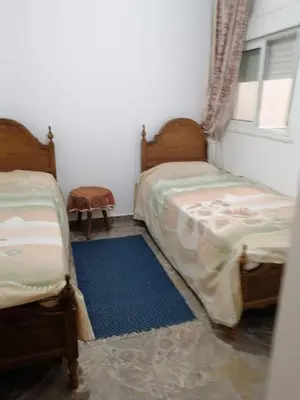 a bedroom with two beds and a blue rug at Entire home in Tangier, Morocco in Oulad Akkou