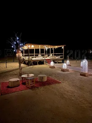 a group of tables in the middle of a field at night at DesertGlow camp in Merzouga