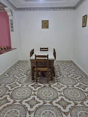 a dining room with a table and chairs on a carpet at اقامااات رضى in Aït Saïd