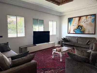 a living room with couches and a flat screen tv at Maison De Maitre in Fès