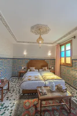 a bedroom with a large bed and a table at Riad Al Mozyane in Fès