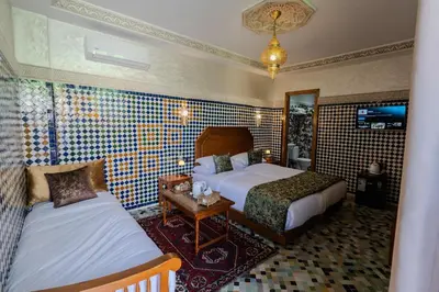 a hotel room with two beds and a tv at Riad Al Mozyane in Fès