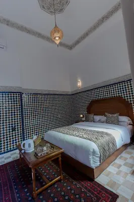 a bedroom with a large bed and a table at Riad Al Mozyane in Fès