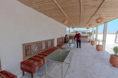 a person standing in a room with benches and tables at Riad Al Mozyane in Fès