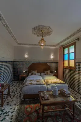 a bedroom with a large bed and a table at Riad Al Mozyane in Fès