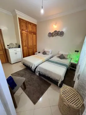 a bedroom with two beds and a table and a kitchen at Appartement cosy à Fès in Fès