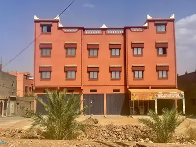 a large orange building in front of a building at Tinzouline in Tinzouline