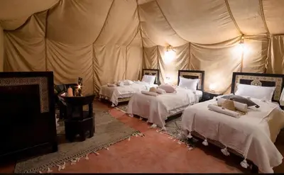 a bedroom with three beds in a tent at Shahrazad Nights Desert Camp in Merzouga