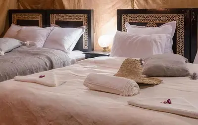 two white beds with pillows and a teddy bear on them at Shahrazad Nights Desert Camp in Merzouga