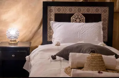 a bedroom with a black and white bed with a lamp at Shahrazad Nights Desert Camp in Merzouga