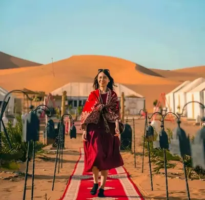 a woman in a red dress standing on a red carpet at Staying Desert Luxury Camp in Merzouga