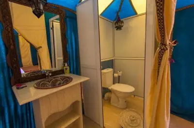 a bathroom with a toilet and a sink and a mirror at Staying Desert Luxury Camp in Merzouga