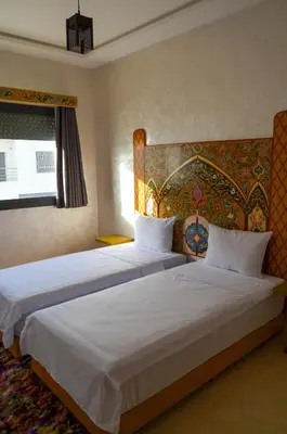 a bedroom with two beds and a painting on the wall at Appartement Nadine Fès in Fès