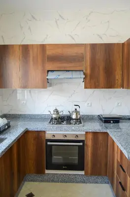 a kitchen with wooden cabinets and a stove top oven at Appartement Nadine Fès in Fès
