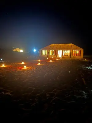 a building on the beach at night with lights at Arawan Luxury Desert Camp at Erg Lihoudi in Mhamid