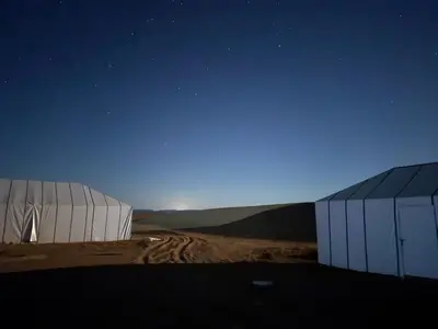 two white buildings in a desert under a night sky at Arawan Luxury Desert Camp at Erg Lihoudi in Mhamid