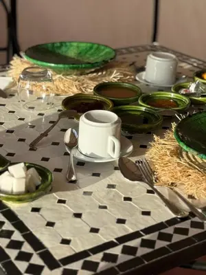 a table with green and white plates and utensils at Arawan Luxury Desert Camp at Erg Lihoudi in Mhamid