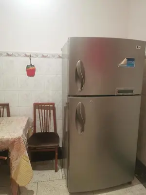 a refrigerator in a kitchen with a table and a chair at Appart à merjane in Meknès
