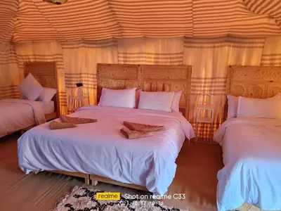 a bedroom with two beds with white sheets at Tenere luxury camp in Merzouga