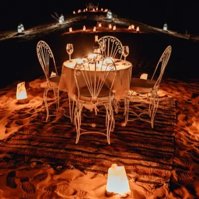 a table with chairs and wine glasses on a rug at Tenere luxury camp in Merzouga
