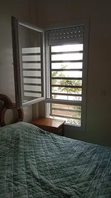 a bedroom with a bed and two large windows at La maison verte in Fès