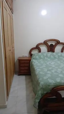 a bedroom with a bed with a green comforter and a wooden cabinet at La maison verte in Fès